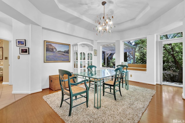 dining room featuring a tray ceiling, hardwood / wood-style flooring, and a notable chandelier