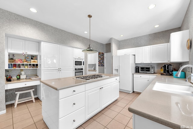 kitchen with hanging light fixtures, appliances with stainless steel finishes, white cabinets, and a kitchen island