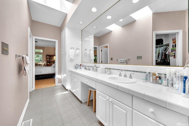 bathroom featuring a skylight, tile patterned flooring, decorative backsplash, and vanity