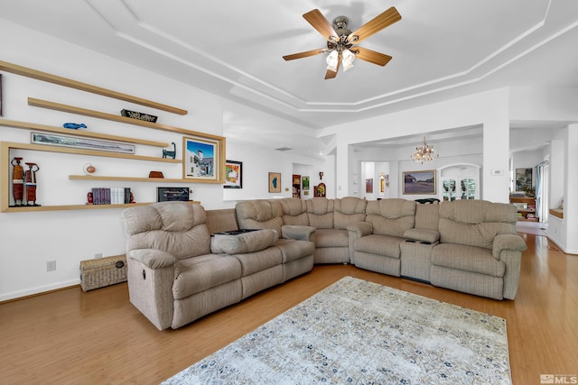 living room featuring ceiling fan with notable chandelier, hardwood / wood-style floors, and a tray ceiling