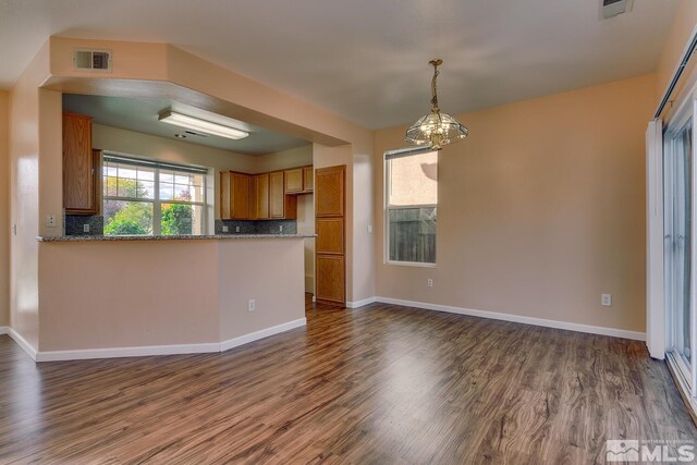 kitchen featuring kitchen peninsula, dark hardwood / wood-style floors, a chandelier, and tasteful backsplash