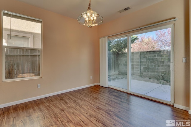 spare room featuring hardwood / wood-style flooring and a chandelier