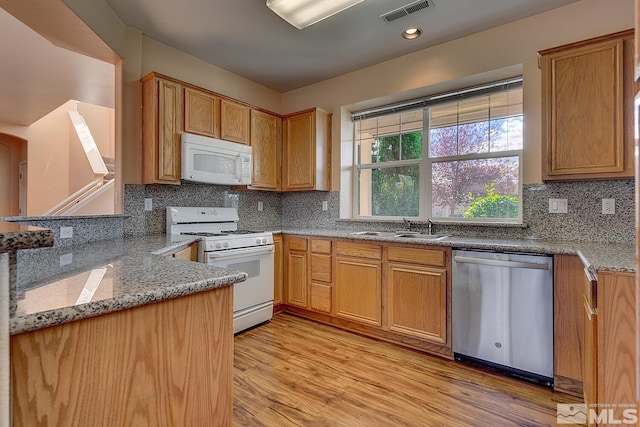 kitchen with light wood-type flooring, white appliances, sink, and light stone countertops