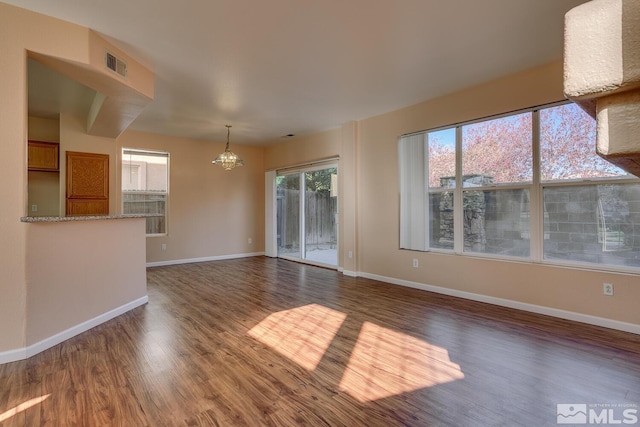 unfurnished living room with dark wood-type flooring and an inviting chandelier