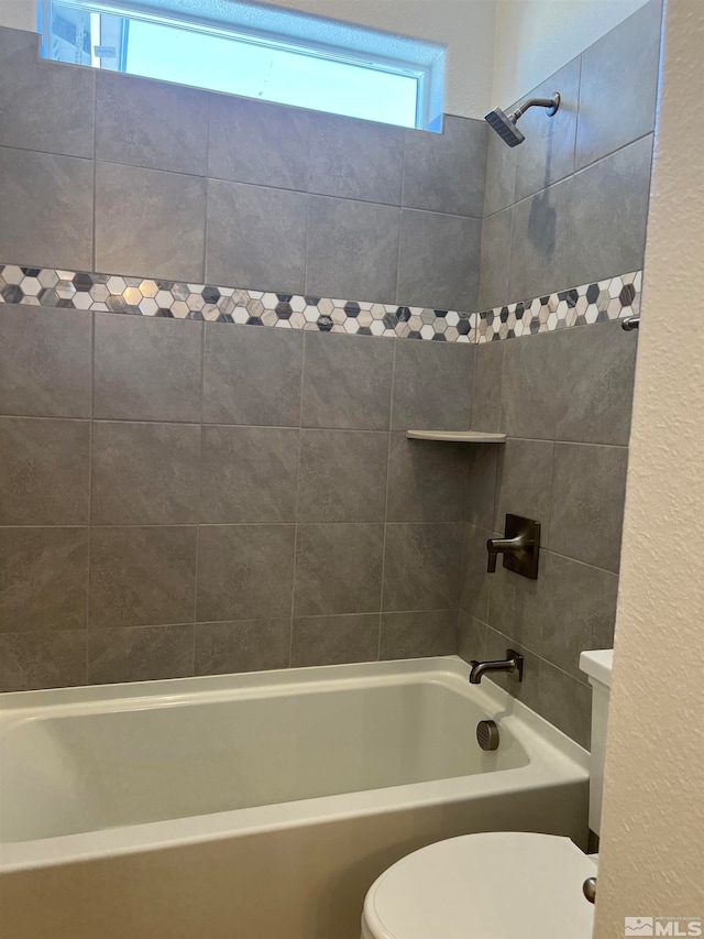 bathroom featuring toilet and tiled shower / bath combo