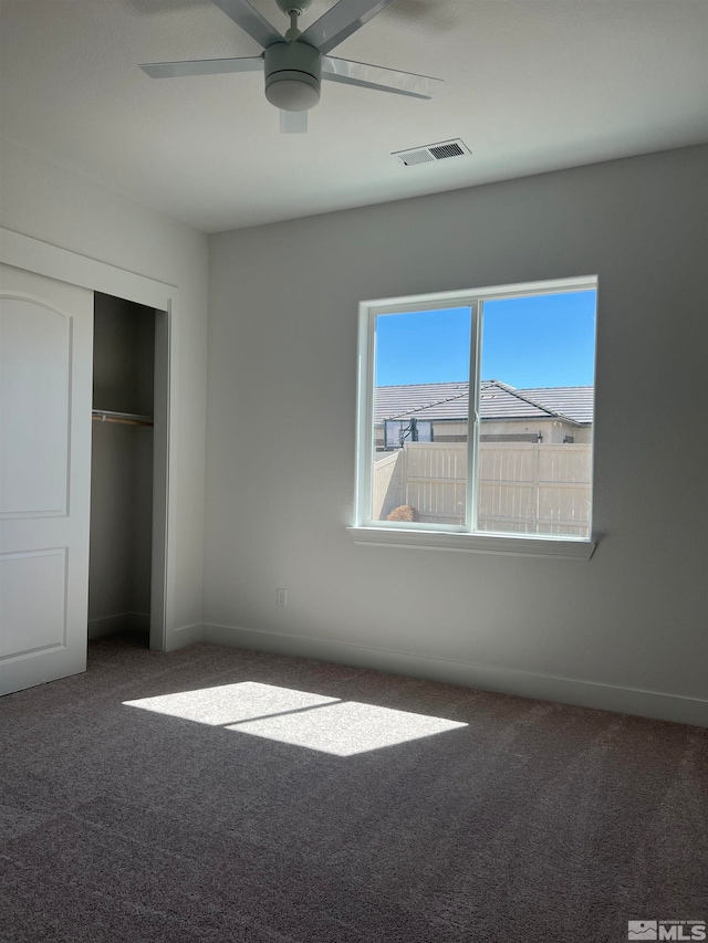 unfurnished bedroom featuring dark carpet, ceiling fan, and a closet