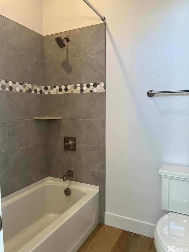 bathroom with hardwood / wood-style floors, toilet, and tiled shower / bath combo