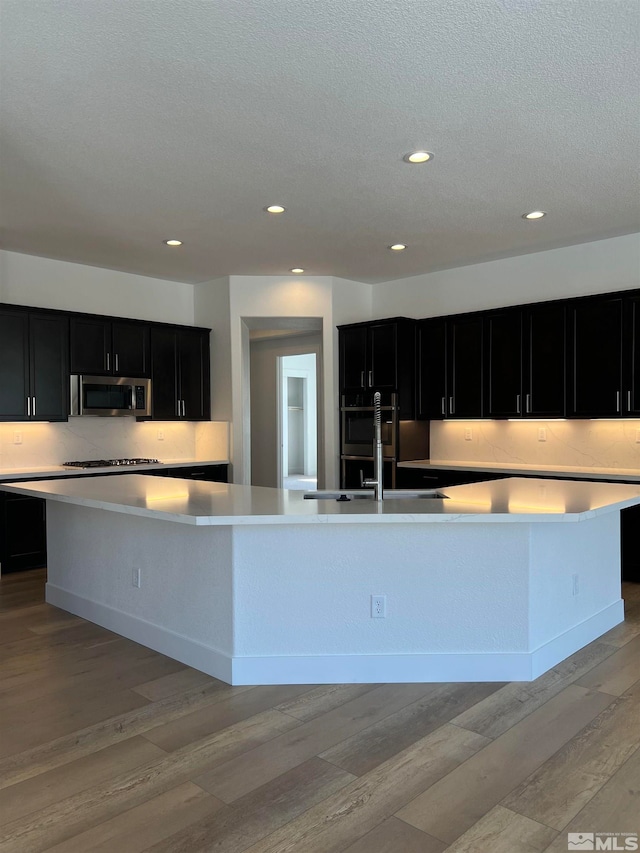 kitchen featuring gas stovetop, sink, a large island, and light wood-type flooring