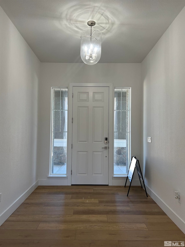 entrance foyer with a wealth of natural light, dark hardwood / wood-style floors, and an inviting chandelier