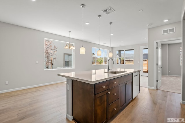 kitchen featuring a kitchen island with sink, light hardwood / wood-style flooring, dark brown cabinets, sink, and pendant lighting