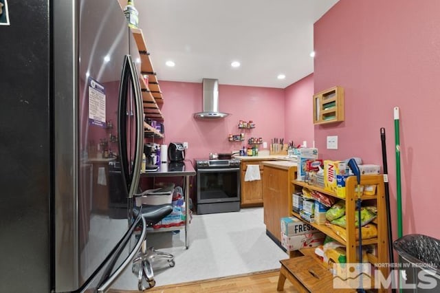 kitchen with wall chimney range hood, appliances with stainless steel finishes, and light wood-type flooring