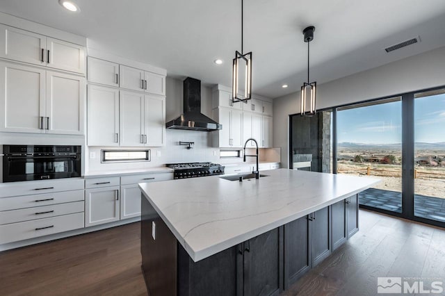 kitchen featuring sink, oven, wall chimney range hood, and white cabinetry