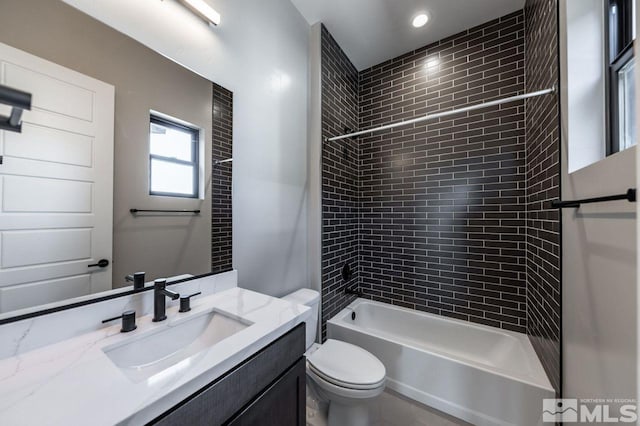 full bathroom featuring tiled shower / bath, vanity, and toilet