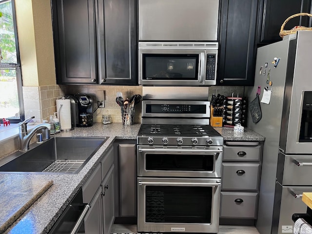 kitchen featuring a healthy amount of sunlight, sink, appliances with stainless steel finishes, and tasteful backsplash