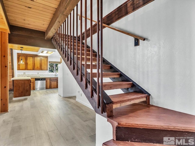 stairs featuring hardwood / wood-style flooring, beam ceiling, and sink