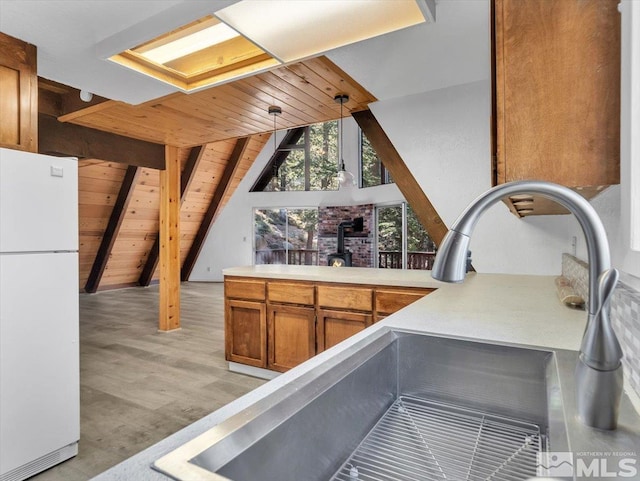 kitchen with wood ceiling, white fridge, sink, hanging light fixtures, and lofted ceiling with beams