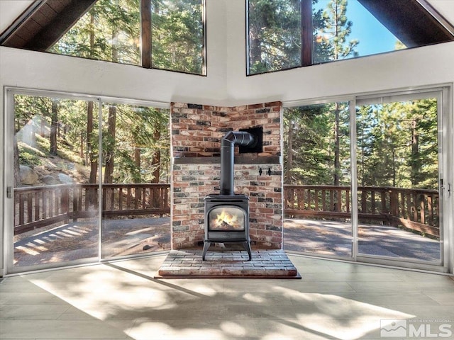 unfurnished living room with a high ceiling, a wealth of natural light, and a wood stove