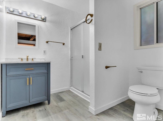 bathroom with an enclosed shower, toilet, hardwood / wood-style flooring, and vanity