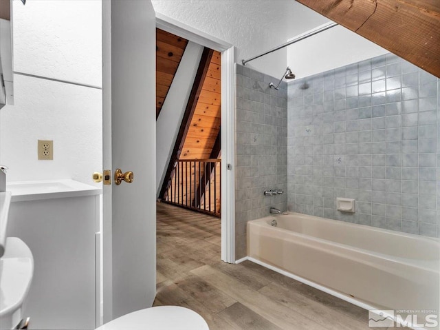 full bathroom featuring wood-type flooring, toilet, tiled shower / bath, and vanity