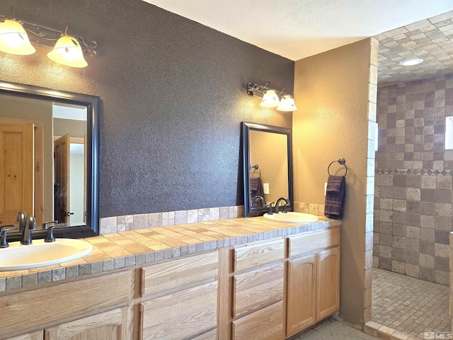 bathroom with a sink, double vanity, and a textured wall