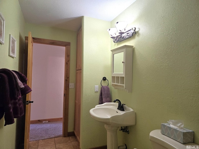 half bath featuring baseboards, toilet, and tile patterned flooring