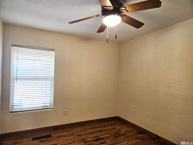 empty room with visible vents, baseboards, dark wood-style floors, and a ceiling fan