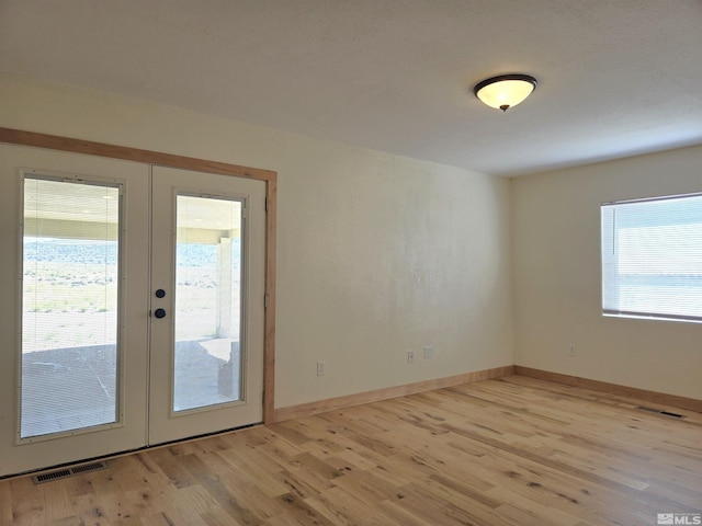 spare room with french doors, baseboards, visible vents, and light wood-style flooring