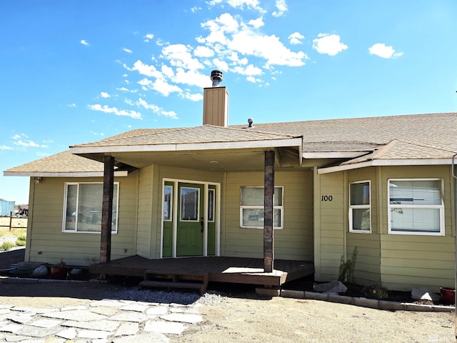 rear view of property with roof with shingles and a chimney