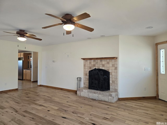 unfurnished living room featuring baseboards, wood finished floors, and a fireplace with raised hearth