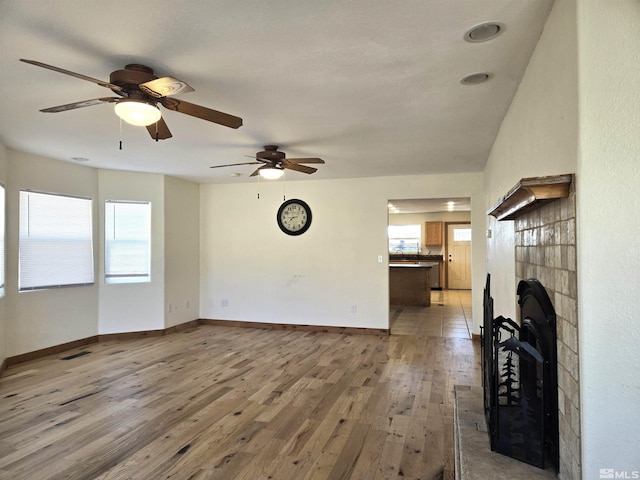 unfurnished living room featuring visible vents, baseboards, light wood-style flooring, and a fireplace