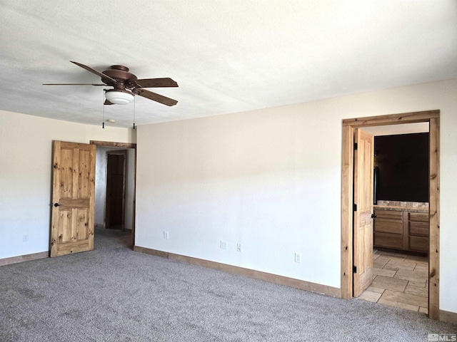 unfurnished bedroom with connected bathroom, baseboards, and carpet flooring