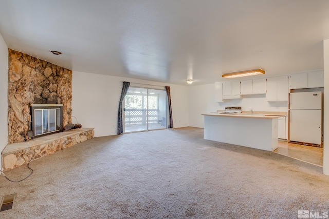 unfurnished living room featuring a stone fireplace and light colored carpet