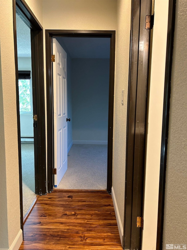 hall featuring dark wood-type flooring and a baseboard heating unit