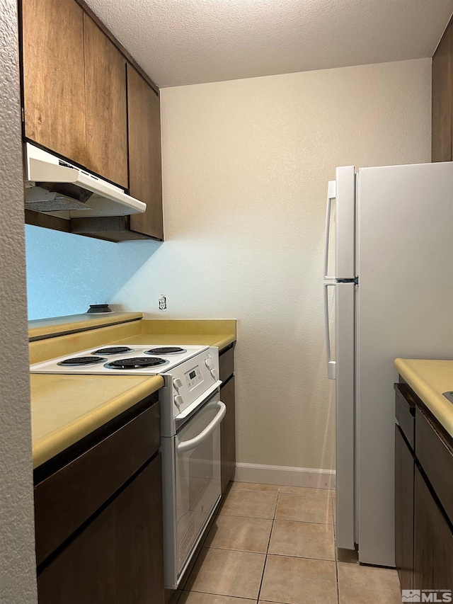 kitchen featuring dark brown cabinets, white appliances, light tile patterned floors, and a textured ceiling