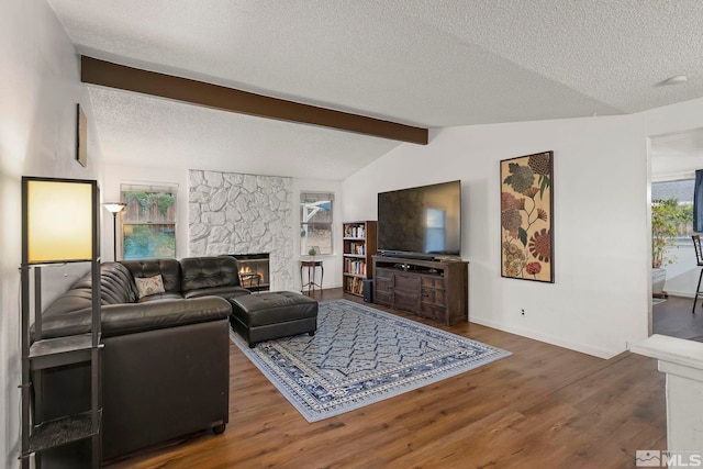 living room with a textured ceiling, a fireplace, lofted ceiling with beams, and dark wood-type flooring