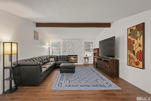 living room with a stone fireplace, vaulted ceiling with beams, a textured ceiling, and hardwood / wood-style floors