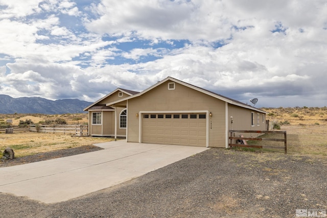 single story home with a mountain view, a rural view, and a garage