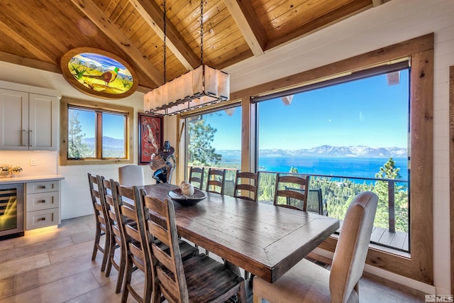 tiled dining space with beverage cooler, lofted ceiling with beams, a water and mountain view, and wooden ceiling