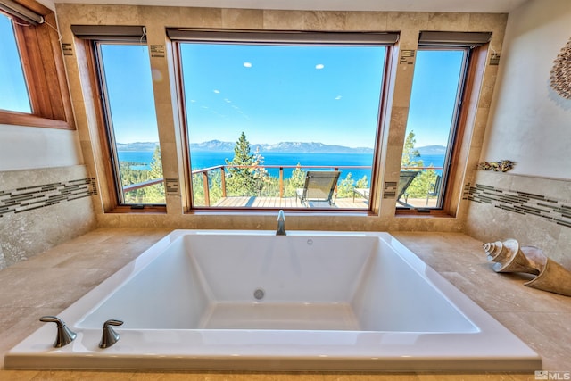 bathroom featuring a tub to relax in and a water and mountain view