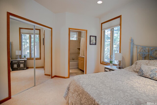 bedroom featuring ensuite bathroom, a closet, and light carpet