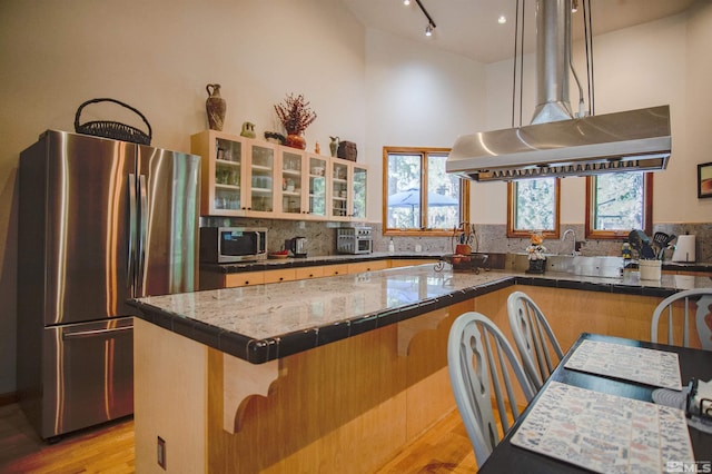 kitchen with stainless steel refrigerator, a kitchen island, a healthy amount of sunlight, and light wood-type flooring