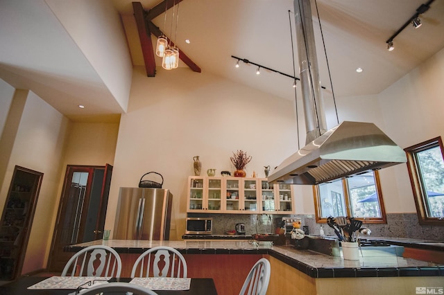 kitchen featuring tasteful backsplash, stainless steel refrigerator, high vaulted ceiling, and track lighting