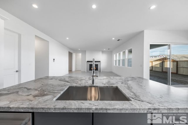 kitchen with light stone countertops, plenty of natural light, and sink