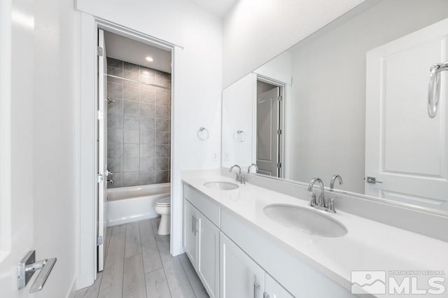 full bathroom with tiled shower / bath, hardwood / wood-style floors, vanity, and toilet