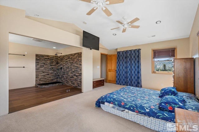 bedroom with vaulted ceiling, ceiling fan, a fireplace, and hardwood / wood-style floors