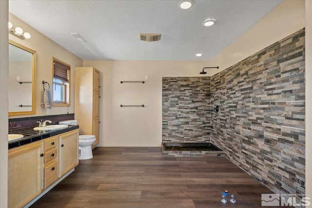 bathroom featuring hardwood / wood-style flooring, walk in shower, vanity, and toilet