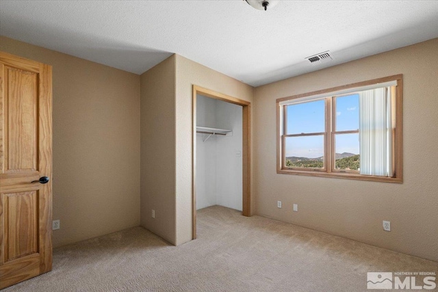 unfurnished bedroom featuring a closet, light colored carpet, and a textured ceiling