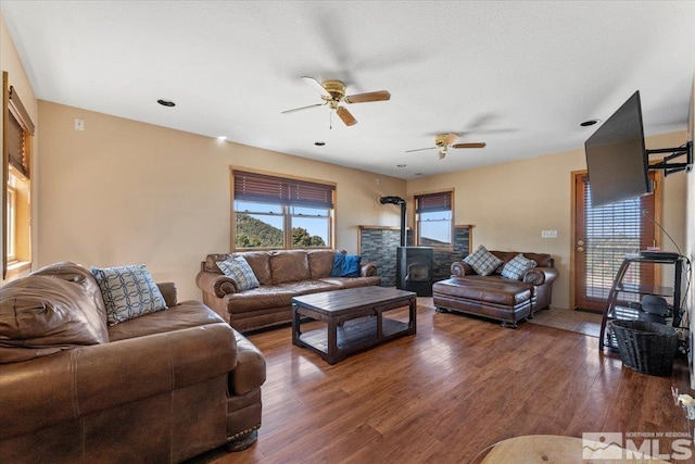 living room with ceiling fan, dark hardwood / wood-style floors, and a wood stove