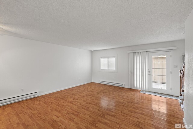 unfurnished room with a baseboard radiator, light wood-type flooring, and a textured ceiling