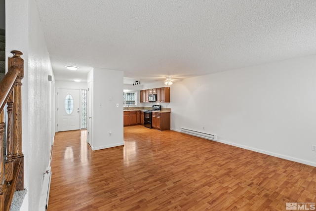 unfurnished living room featuring a textured ceiling, ceiling fan, light hardwood / wood-style flooring, a baseboard radiator, and sink